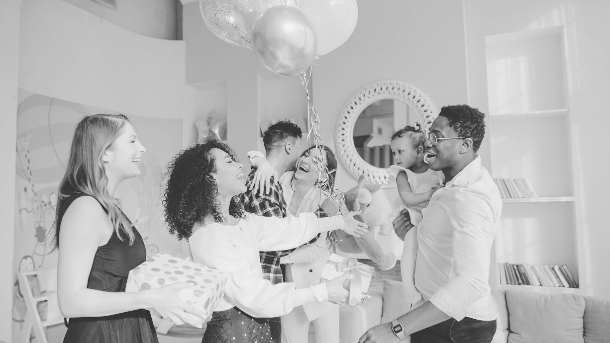 Group of people celebrating with balloons and a mirror in a room.