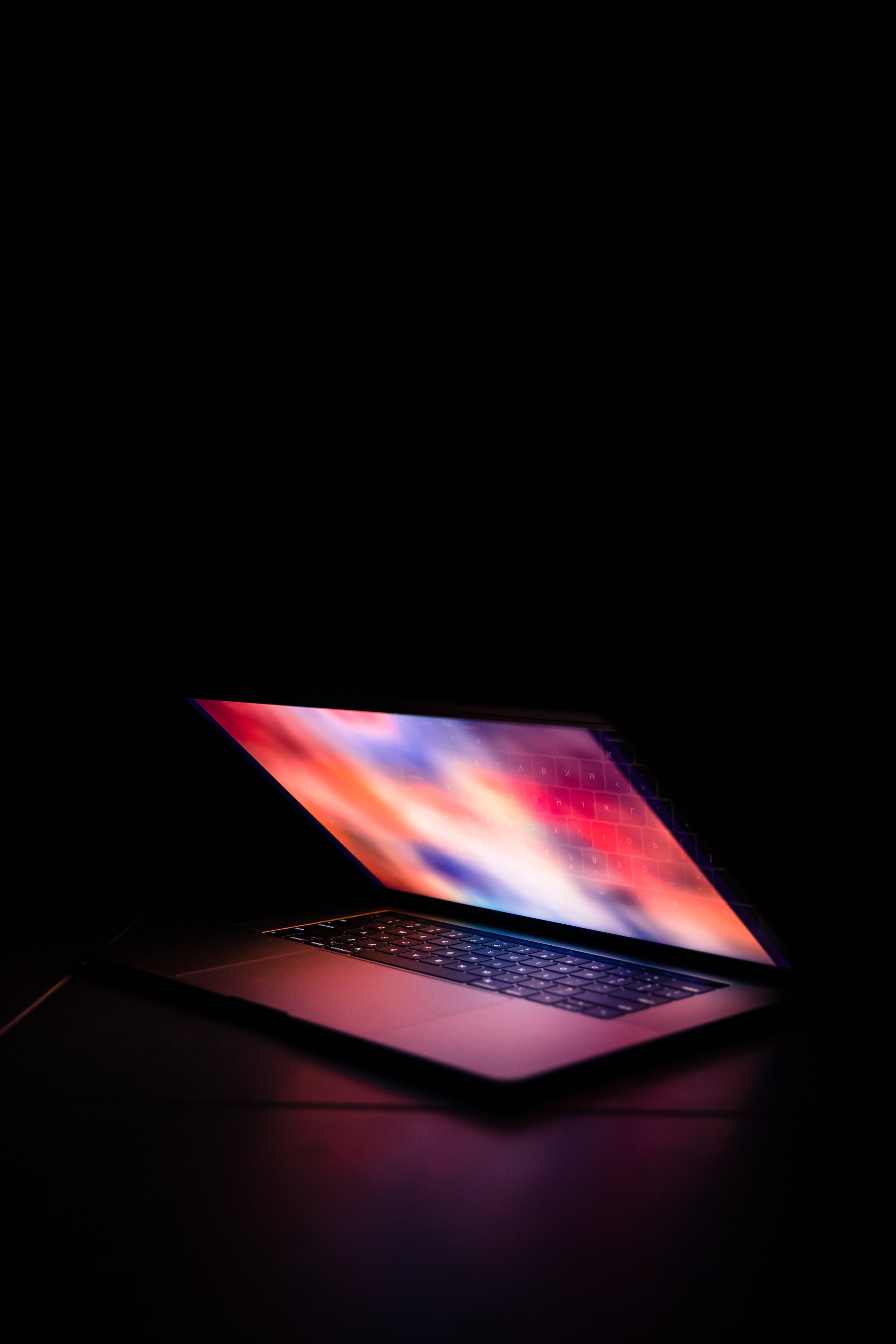 a glowing laptop sitting open surrounded by darkness 