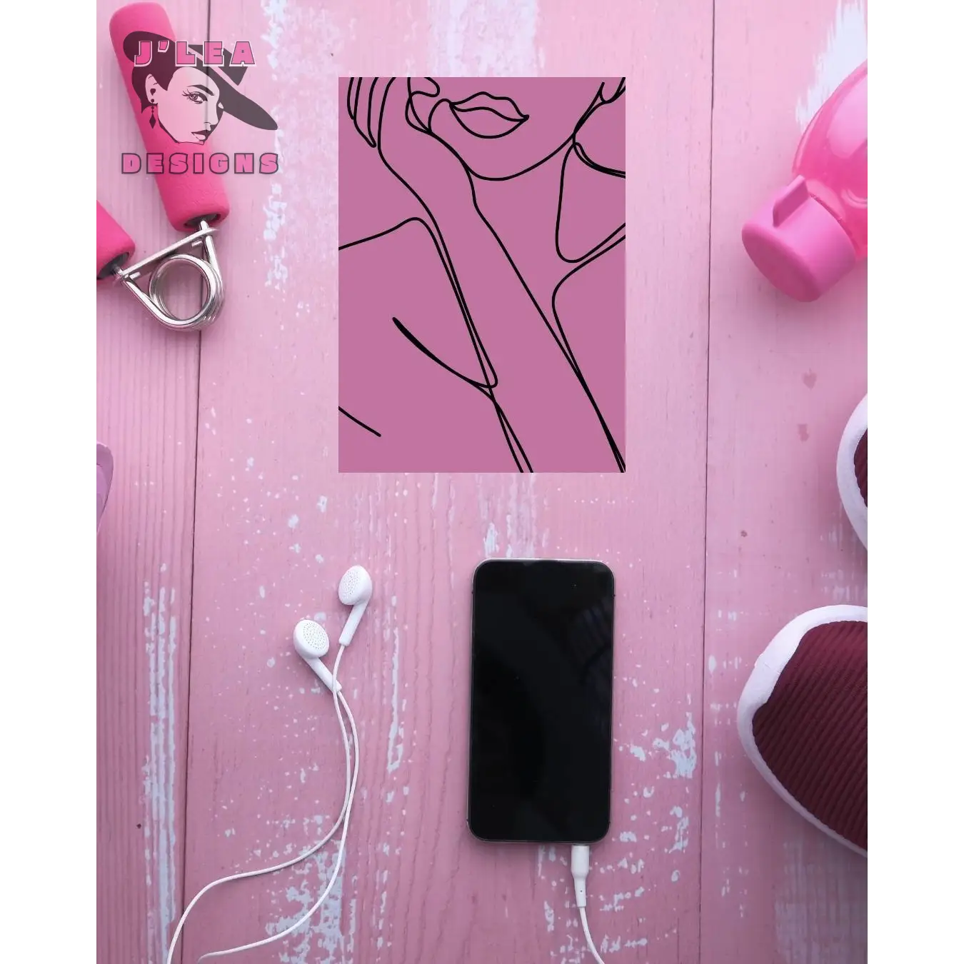 Black phone with white earbuds on a pink wooden surface with fitness equipment.
